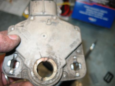 1992 Ford Bronco - Hand holding a cast aluminum engine component, likely a timing cover or housing, showing rear face with center bore.