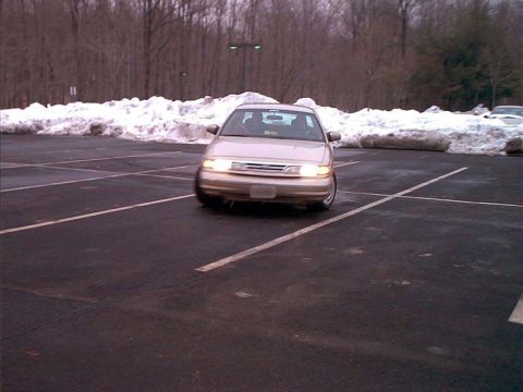 2000 Ford Crown Victoria - A tan sedan is parked in a lot with snow piled up around the edges.