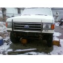 1989 Ford Bronco - A white 1989 Ford Bronco is seen from the front, covered in snow, with a brush guard attached.