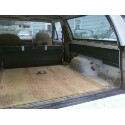 1989 Ford Bronco - The cargo area of an SUV shows a wooden floor and folded rear seats, suggesting a focus on utility or customization.