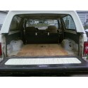 1989 Ford Bronco - The empty cargo area of a white SUV, showing a wooden floor and folded rear seats.