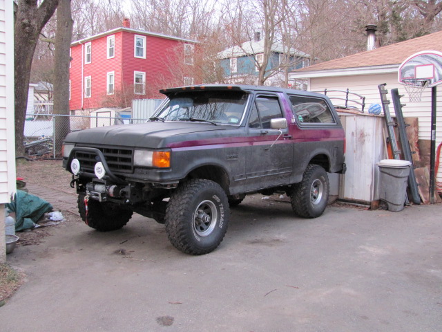 1989 Ford Bronco with aftermarket bumper, winch, and off-road tires parked in a driveway