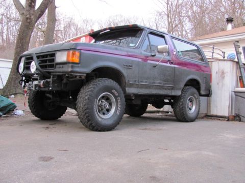 1989 Ford Bronco - This modified Ford Bronco sits in a driveway, showing off its off-road tires and custom front bumper.