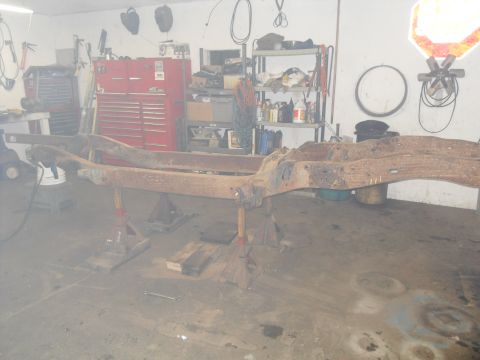 1997 Ford Ranger - A heavily rusted vehicle frame is supported by jack stands in a workshop setting.