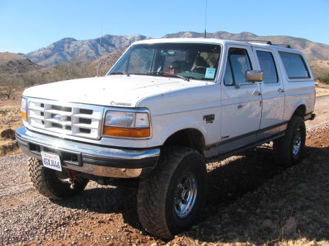 1996 Ford C-350 (Centurion Conversions) - White 1996 Ford C-350 (Centurion Conversions) SUV with off-road tires on a dirt road.