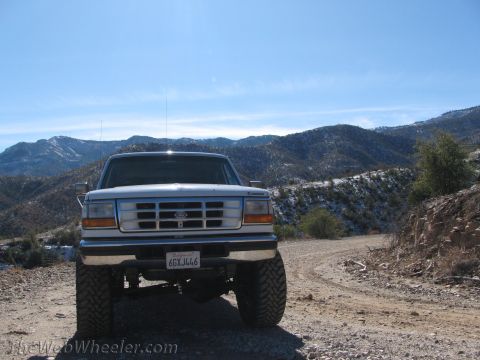 1996 Ford C-350 (Centurion Conversions) - A white 1996 Ford F-Series truck is parked on a dirt road with snow-dusted mountains in the distance.