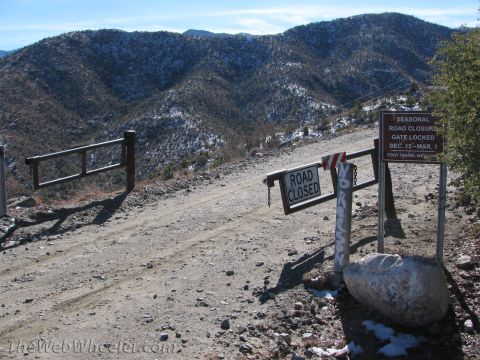 1996 Ford C-350 (Centurion Conversions) - A seasonal road closure gate is locked, blocking access to the mountain road.