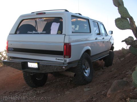 1996 Ford C-350 (Centurion Conversions) - White Ford Bronco SUV with off-road modifications parked on a dirt trail.
