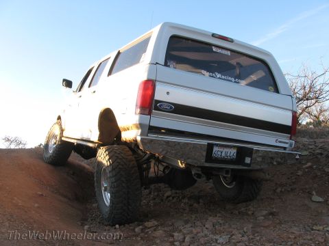 1996 Ford C-350 (Centurion Conversions) - This lifted Ford Bronco Centurion is navigating a steep, rocky incline under a clear blue sky.