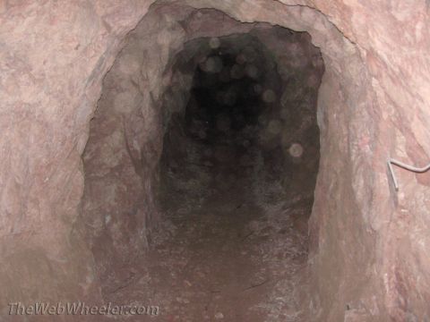 1996 Ford C-350 (Centurion Conversions) - The entrance to a dark cave tunnel, with rough, unworked rock walls.