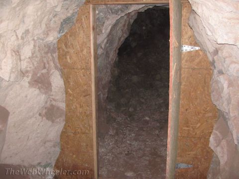1996 Ford C-350 (Centurion Conversions) - A rough cave entrance is framed by wood and particle board, leading into darkness.