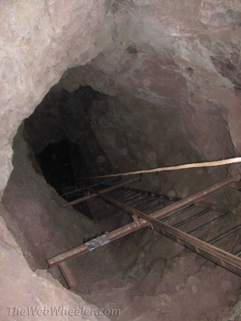 1996 Ford C-350 (Centurion Conversions) - A rope and ladder lead down into a dark cave, suggesting a challenging descent.
