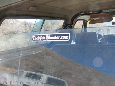 1996 Ford C-350 (Centurion Conversions) - Interior view of a vehicle with stickers and passengers, reflecting the landscape outside.