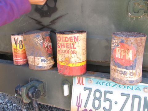 1996 Ford C-350 (Centurion Conversions) - Four vintage oil cans, including Golden Shell and RPM, sit on the rear bumper of a vehicle.