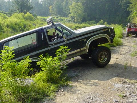 1980 Ford Bronco - A lifted 1980 Ford Bronco tackles a rough trail, with another vehicle visible in the background.
