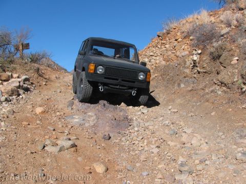 1996 Ford C-350 (Centurion Conversions) - SUV navigates a steep, rocky incline under a clear blue sky.