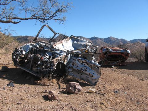 1996 Ford C-350 (Centurion Conversions) - Two heavily damaged vehicles sit in a dry, arid landscape under a clear blue sky.