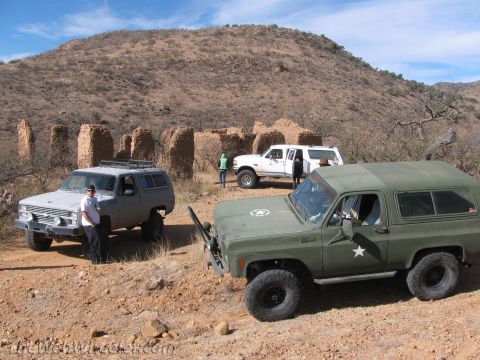 1996 Ford C-350 (Centurion Conversions) - A group of off-road vehicles are parked near ancient ruins in a desert environment.