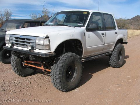 1996 Ford C-350 (Centurion Conversions) - Modified 1995 Ford Explorer Sport Trac with significant lift and oversized tires in an outdoor setting.