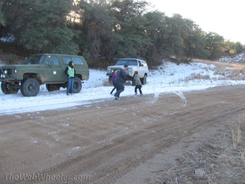 1996 Ford C-350 (Centurion Conversions) - Two SUVs are parked on a dirt road with snow on the ground, with people standing near one of them.
