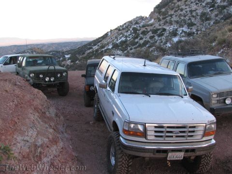 1996 Ford C-350 (Centurion Conversions) - A convoy of off-road vehicles, including a white 1996 Ford C-350 Centurion Conversion, parked on a mountain trail.