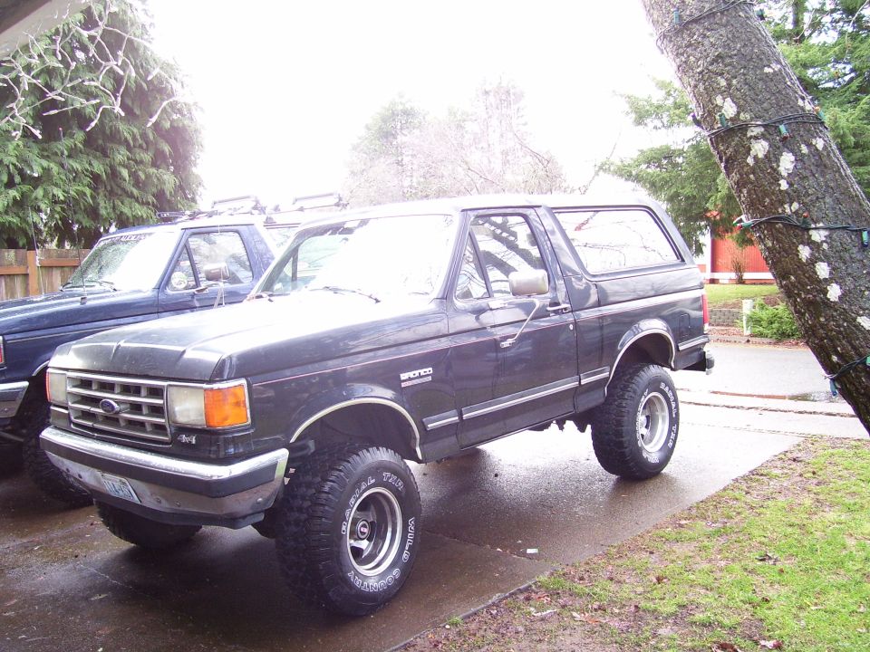 Dark gray 1988 Ford Bronco parked next to a blue truck