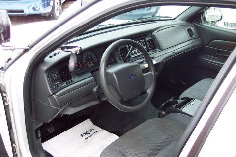 2001 Ford Crown Victoria - Interior view of a 2001 Ford Crown Victoria, the dashboard, steering wheel, and front seats. An Exon Superflo floor mat is visible.