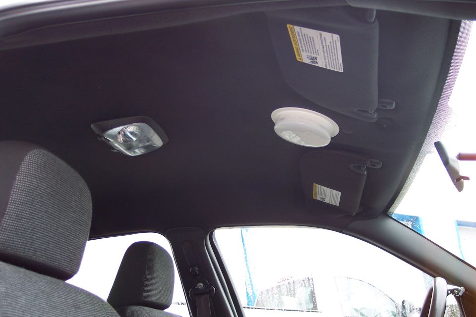 Car interior ceiling with two dome lights, two sun visors, and part of the front seats visible
