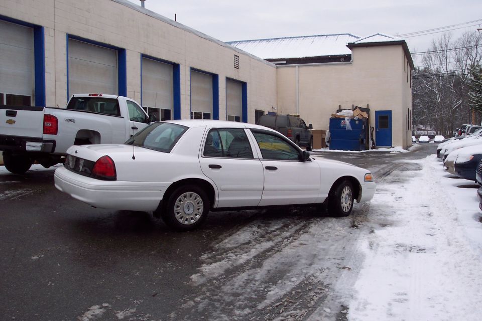 2001 Ford Crown Victoria parked on a snowy lot next to a white pickup truck
