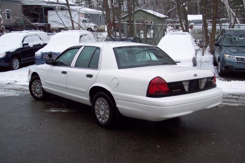 2001 Ford Crown Victoria - A white 2001 Ford Crown Victoria is seen from the rear quarter angle in a snowy environment.