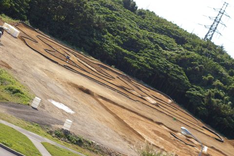 1986 Ford Bronco - RC car track constructed on a sloped terrain, surrounded by vegetation and utility infrastructure.