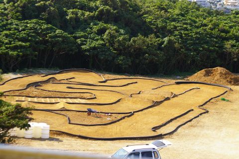 1986 Ford Bronco - An outdoor RC car track is set up with dirt and barriers, ready for racing.
