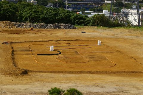 1986 Ford Bronco - A construction site shows trenches dug into the earth, with orange hoses and white barrels marking the area.