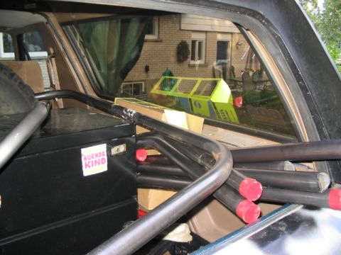 1986 Ford Bronco - The interior of a vehicle is visible, a roll cage and a spare tire, with a sticker on a storage box.