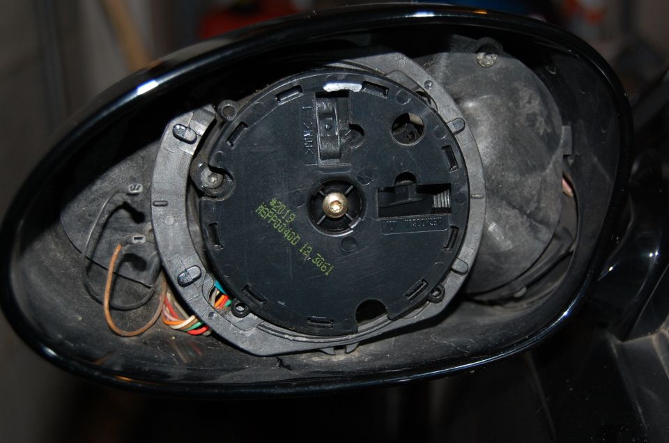 Black side mirror with glass removed showing the actuator motor and wiring