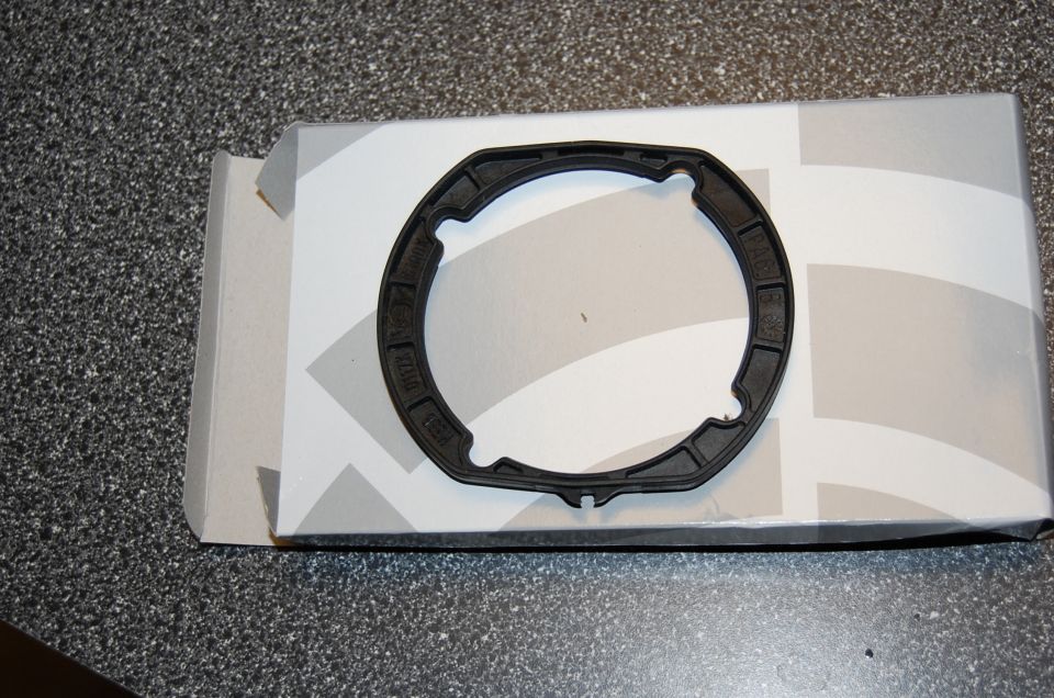 Black molded rubber gasket seal resting on white parts box on speckled counter