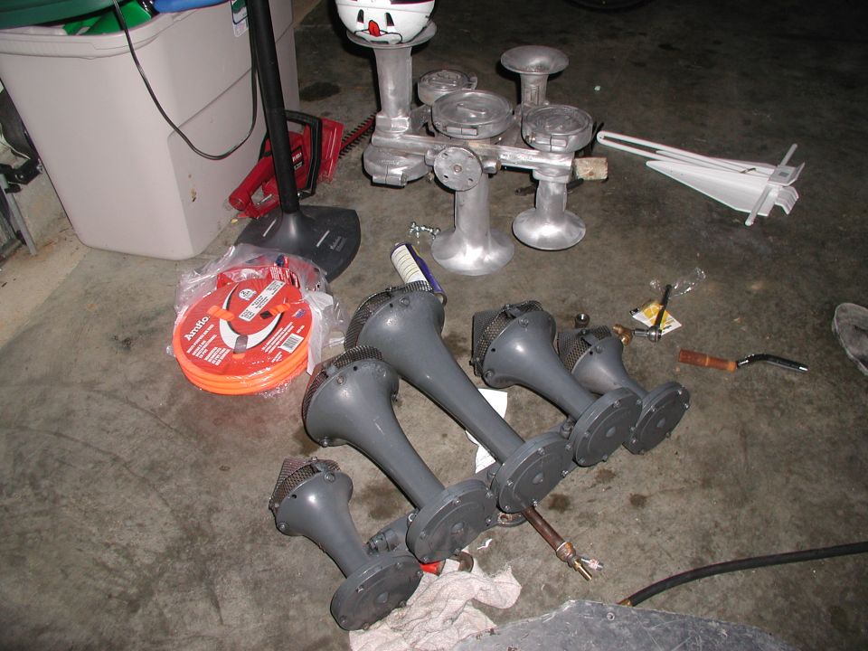 Gray air horns and unpainted aluminum horn castings on a garage floor