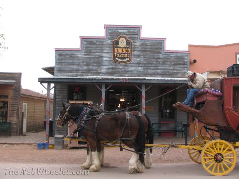 1996 Ford C-350 (Centurion Conversions) - Horse-drawn carriage parked outside the Bronco Trading building, a man seated on the driver's bench.