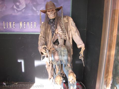 1996 Ford C-350 (Centurion Conversions) - A skeleton dressed as a cowboy, complete with a hat and revolvers, stands in front of a backdrop with text.