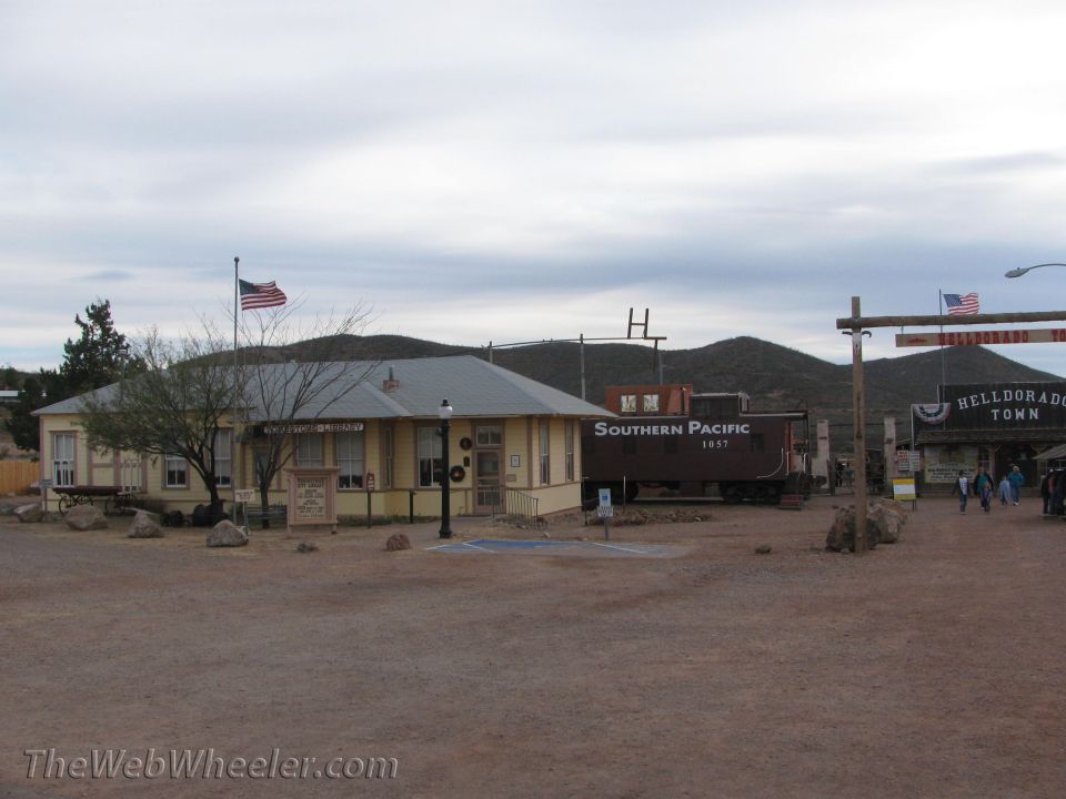 Southern Pacific 1857 train car parked next to a yellow building with an American flag
