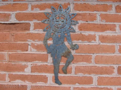 1996 Ford C-350 (Centurion Conversions) - A metal decoration depicting a sun god figure is mounted on a red brick wall.