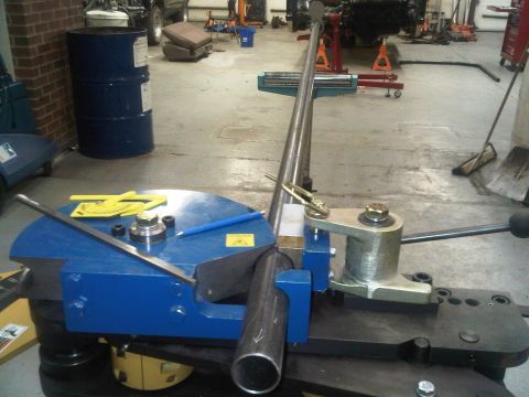 1996 Ford Bronco - A metal tube is being bent on a machine in a workshop setting.