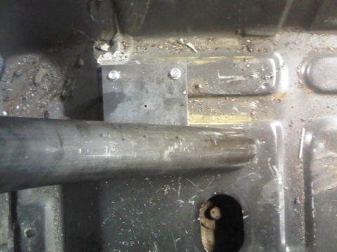 1996 Ford Bronco - Close-up view of the interior floor of a vehicle, revealing a metal pipe and a mounting bracket.