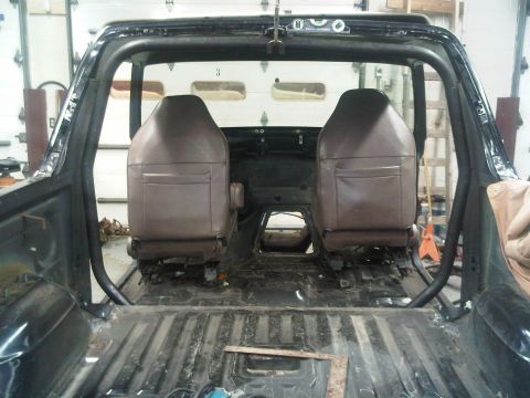 1996 Ford Bronco - Interior of a 1996 Ford Bronco showing custom roll cage and stripped rear cargo area.