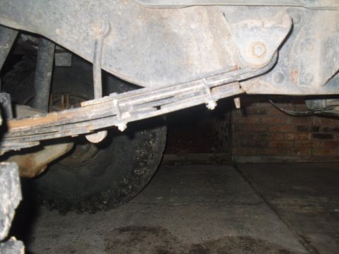 1984 Ford Bronco II - Underside view of a vehicle's rear suspension system, showing leaf springs and a tire.