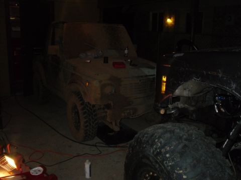 1984 Ford Bronco II - A muddy Suzuki Samurai is parked in a garage, with another vehicle partially visible to its right.