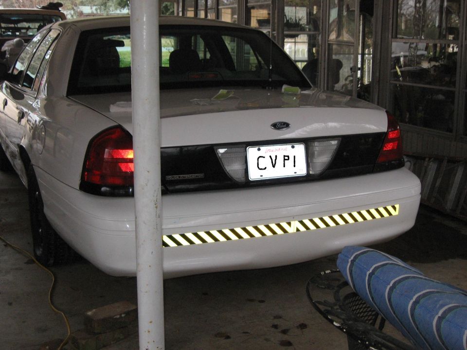 Rear of white Ford Crown Victoria Police Interceptor with CVPI Louisiana plate and reflective bumper stripe