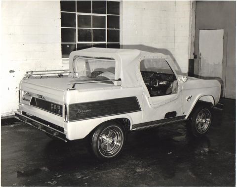 1991 Ford Bronco - This convertible SUV features wood paneling and chrome wheels, seen from the rear 3/4 angle.