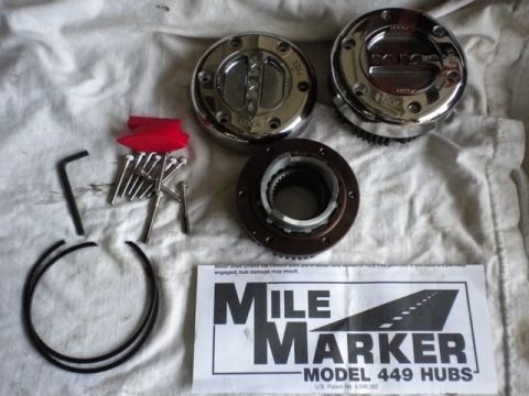 1989 Ford Bronco - Mile Marker hub lockouts and associated hardware are laid out on a white cloth surface.