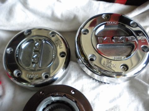 1989 Ford Bronco - Close-up of two chrome MileMarker hubcaps, showing the 'LOCK' and 'FREE' settings.